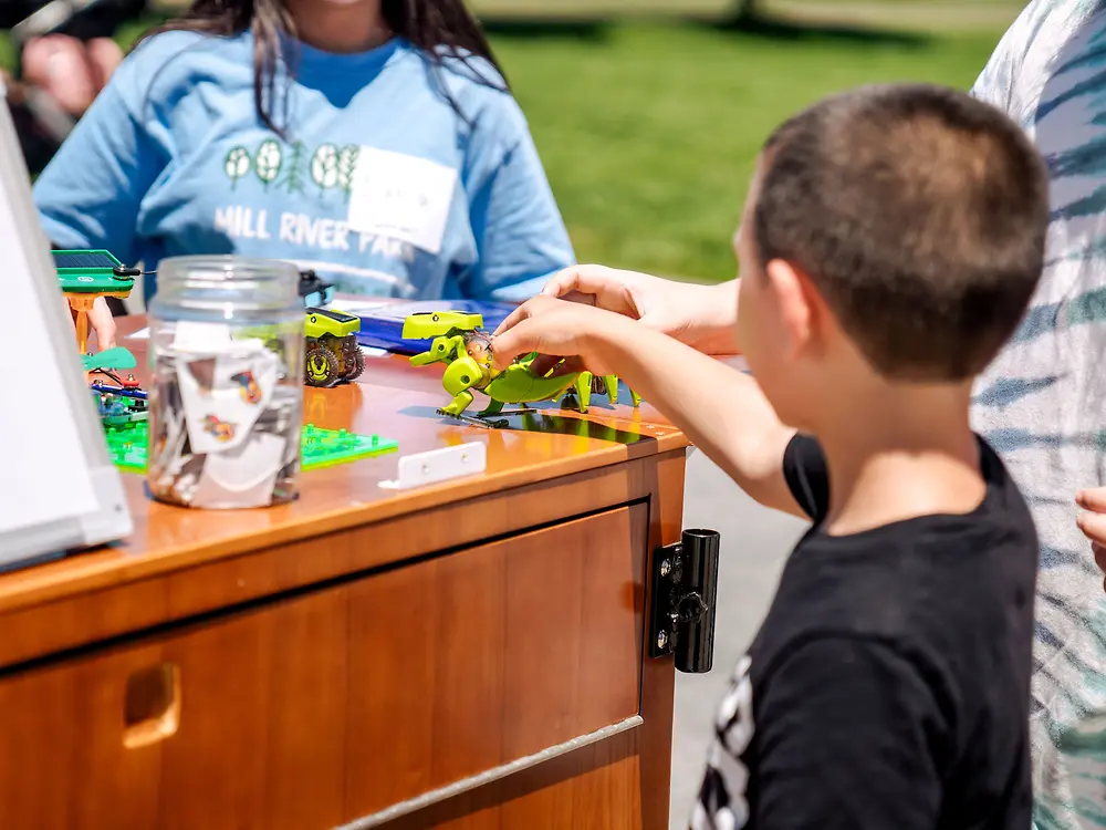 Student plays with a mechanical dinosaur toy.