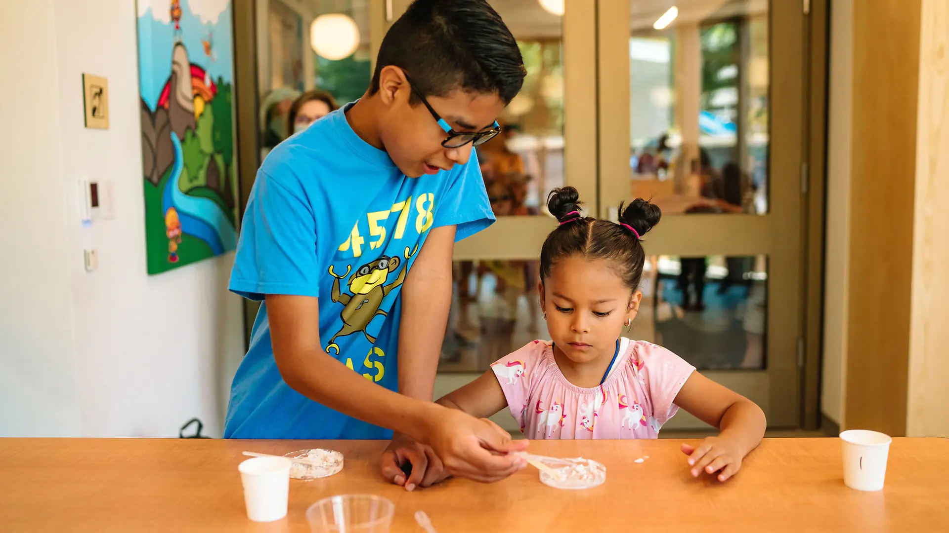 Volunteer aids student in mixing a paste for energy experiment.