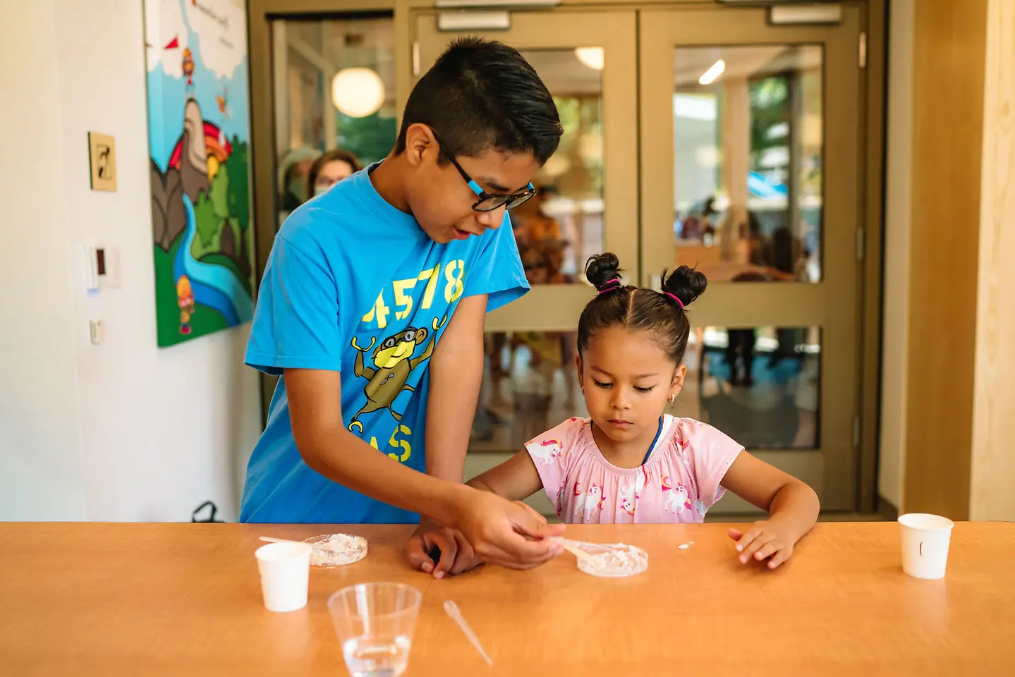 Volunteer aids student in mixing a paste for energy experiment.