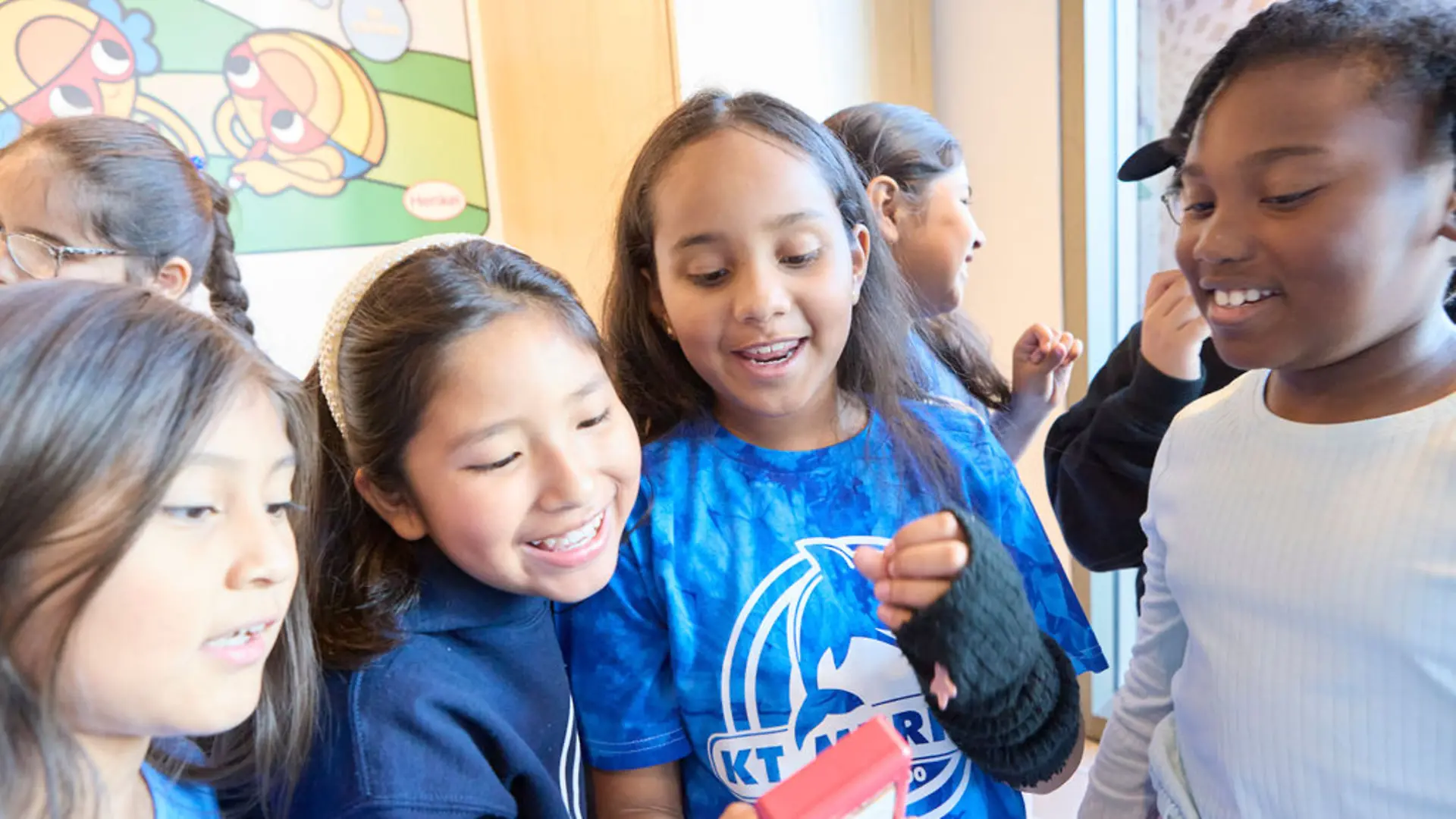 Students smiling excitedly while observing a device in action.