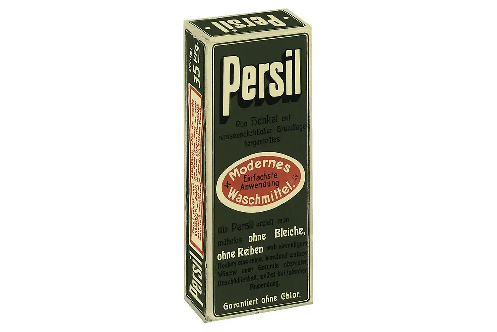 Grüne rechteckige Kartonverpackung des ersten Persil-Waschmittels aus dem Jahr 1907 mit der Aufschrift „Modernes Waschmittel“ und weißen Schriftzügen.